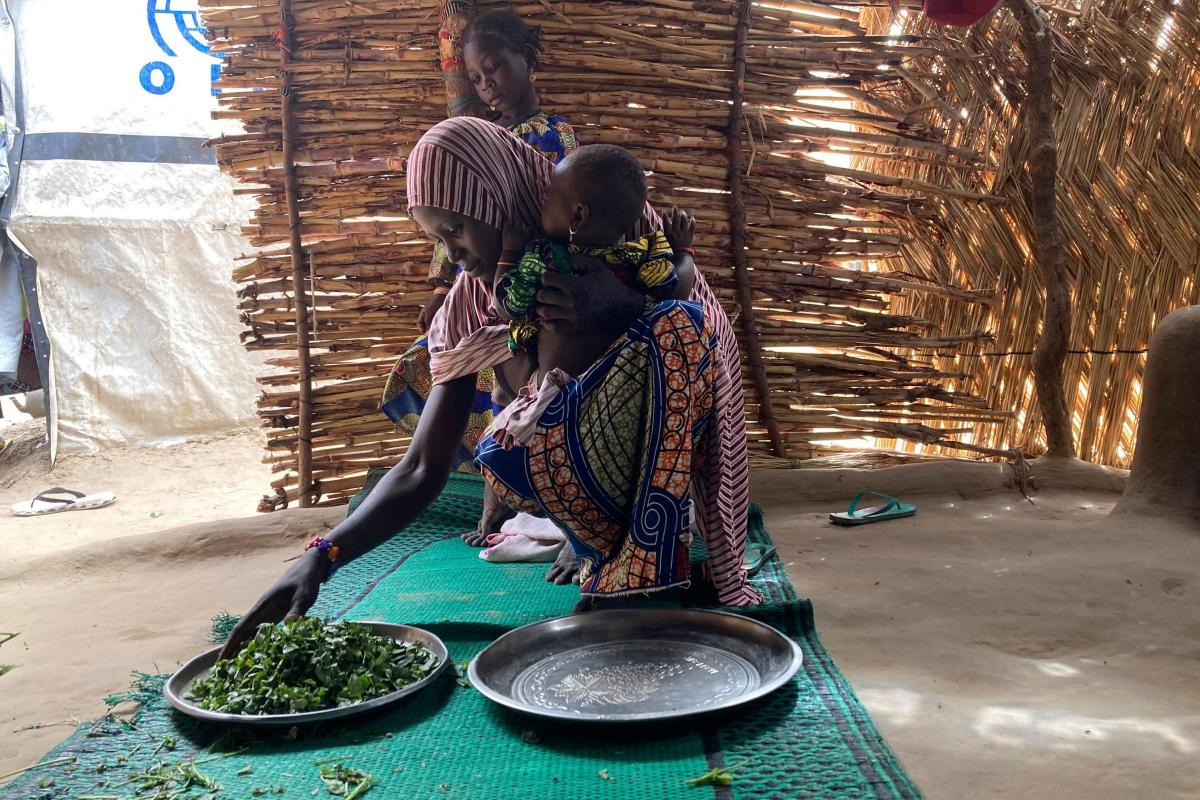 Iza Ali, 25, selects vegetables to prepare a meal for her family at the Jere camp for people displaced by Islamist extremists in Maiduguri, Nigeria, Wednesday, May 4, 2022. Iza Ali’s five children are still waiting to eat at 3 p.m. It’s not the first