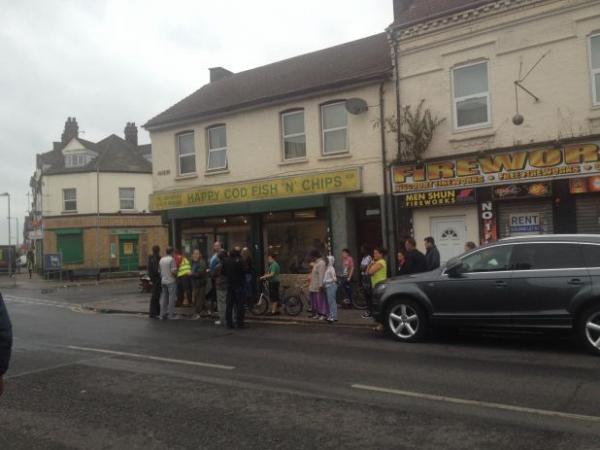 Bystanders outside 'Happy Cod Fish & Chips' on Dock Road